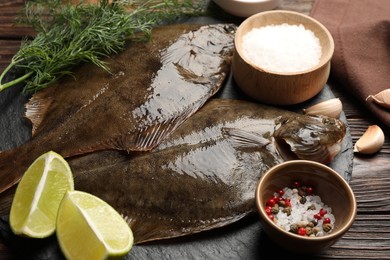 Photo of Fresh flounder fish, spices and products on wooden table, closeup. Raw seafood