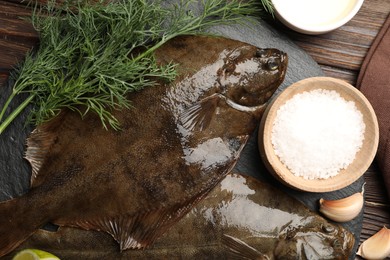 Photo of Fresh flounder fish, salt and products on wooden table, flat lay. Raw seafood