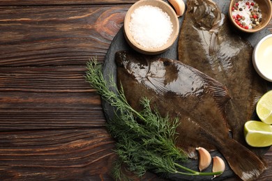 Photo of Fresh flounder fish, spices and products on wooden table, flat lay with space for text. Raw seafood