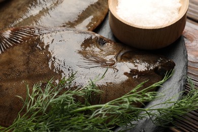 Photo of Fresh flounder fish, salt and dill on wooden table, closeup. Raw seafood