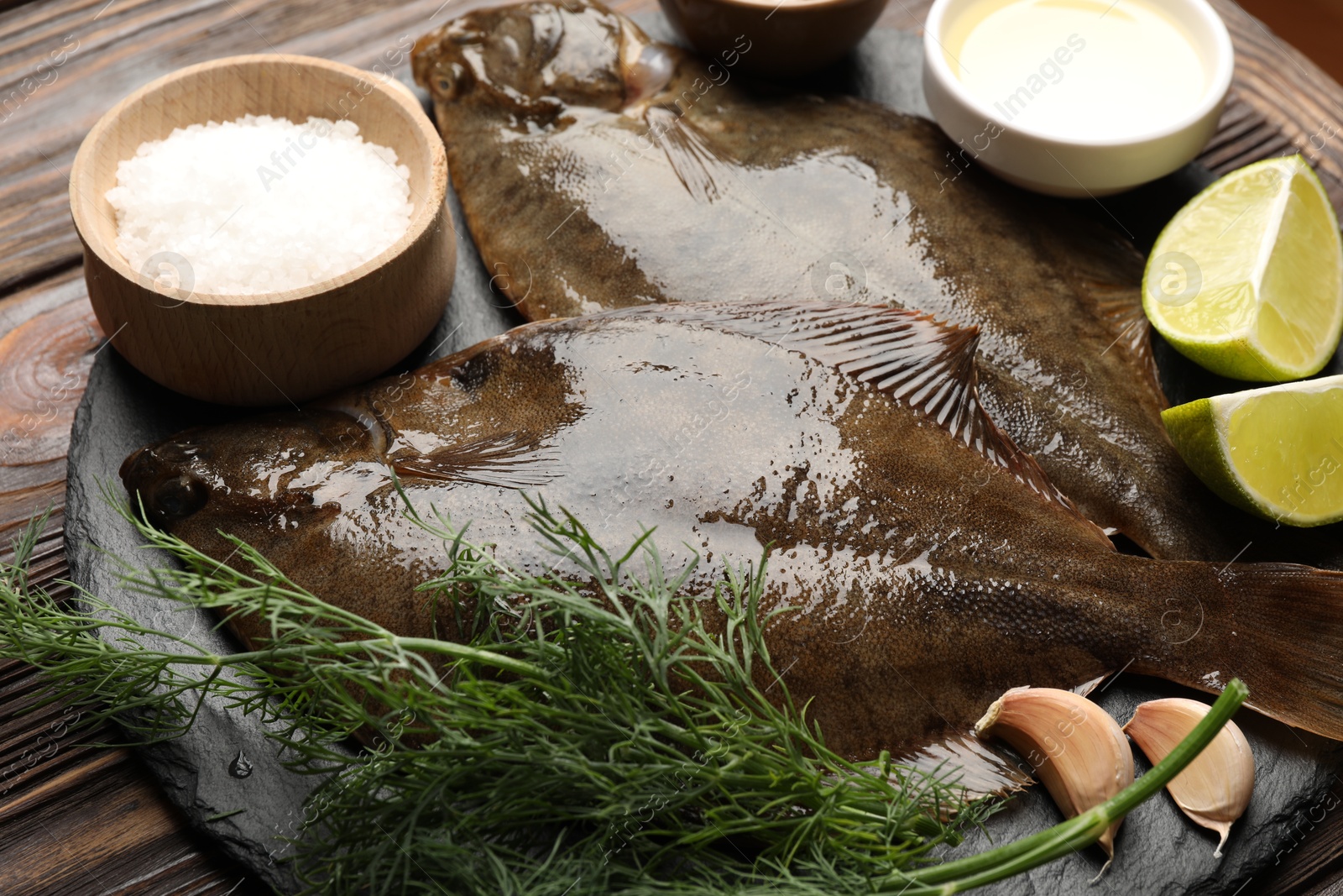Fresh flounder fish, salt and products on wooden table, closeup. Raw seafood Photo of Fresh flounder fish, salt and products on wooden table, closeup. Raw seafood