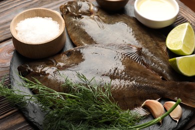 Photo of Fresh flounder fish, salt and products on wooden table, closeup. Raw seafood