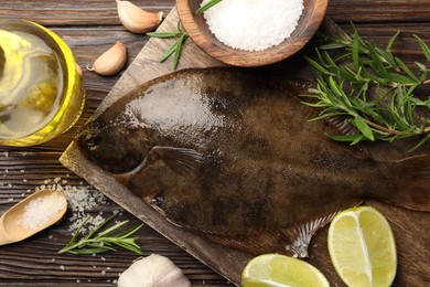 Photo of Fresh flounder fish, salt and products on wooden table, flat lay. Raw seafood
