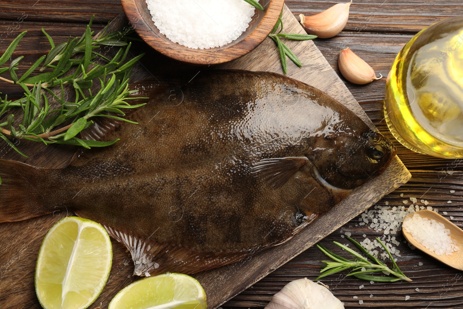 Fresh flounder fish, salt and products on wooden table, flat lay. Raw seafood Photo of Fresh flounder fish, salt and products on wooden table, flat lay. Raw seafood