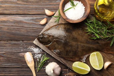 Photo of Fresh flounder fish, salt and products on wooden table, flat lay. Raw seafood
