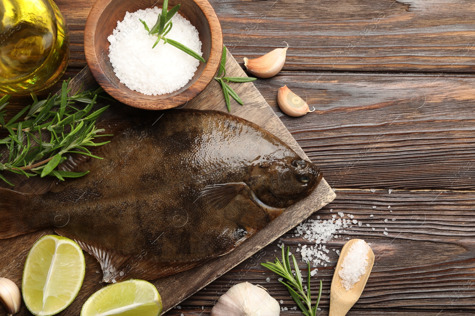 Photo of Fresh flounder fish, salt and products on wooden table, flat lay. Raw seafood