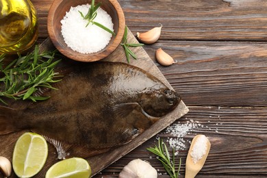Photo of Fresh flounder fish, salt and products on wooden table, flat lay. Raw seafood