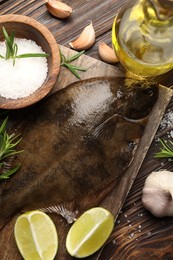 Photo of Fresh flounder fish, salt and products on wooden table, flat lay. Raw seafood