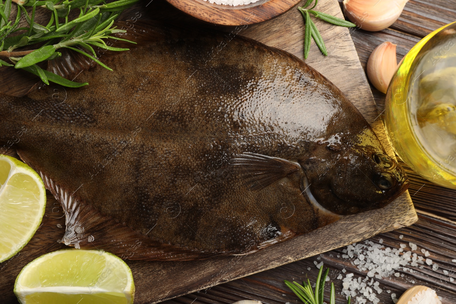 Photo of Fresh flounder fish, salt and products on wooden table, flat lay. Raw seafood