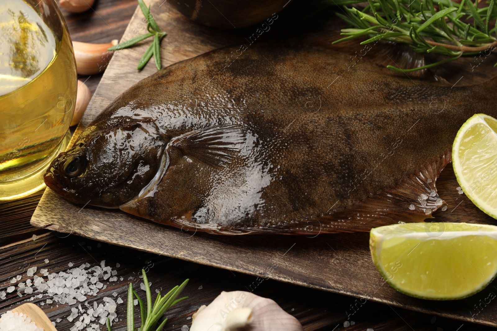 Photo of Fresh flounder fish, salt and products on wooden table, closeup. Raw seafood