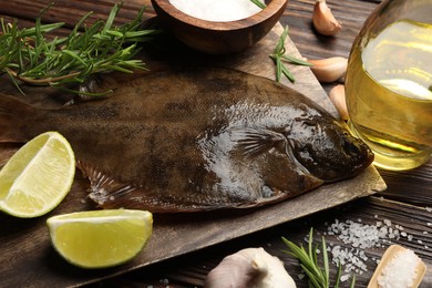 Photo of Fresh flounder fish, salt and products on wooden table, closeup. Raw seafood