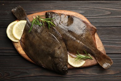 Photo of Fresh flounder fish, lemon and rosemary on wooden table, top view. Raw seafood