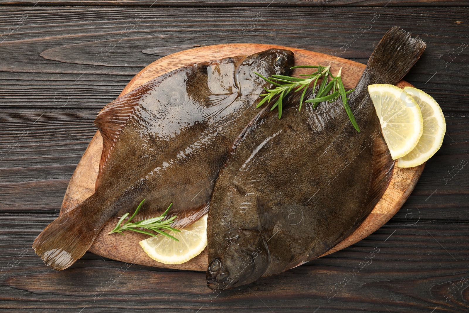 Photo of Fresh flounder fish, lemon and rosemary on wooden table, top view. Raw seafood
