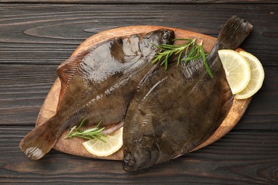 Photo of Fresh flounder fish, lemon and rosemary on wooden table, top view. Raw seafood