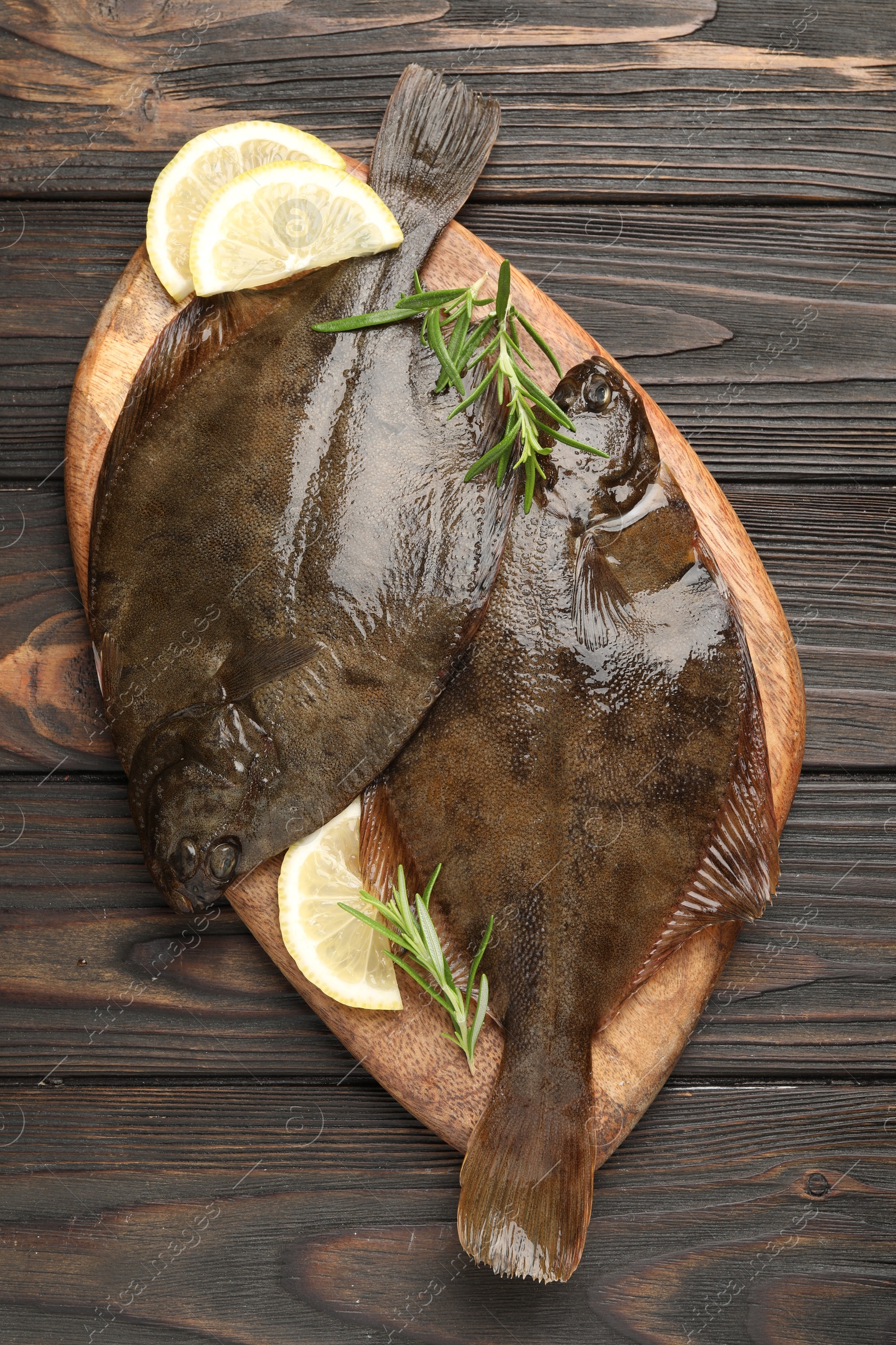 Photo of Fresh flounder fish, lemon and rosemary on wooden table, top view. Raw seafood