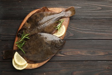 Photo of Fresh flounder fish, lemon and rosemary on wooden table, top view with space for text. Raw seafood