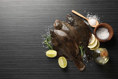 Photo of Fresh flounder fish, salt and products on black wooden table, flat lay with space for text. Raw seafood