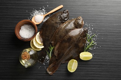Photo of Fresh flounder fish, salt and products on black wooden table, flat lay. Raw seafood