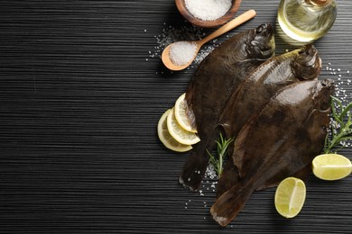 Photo of Fresh flounder fish, salt and products on black wooden table, flat lay with space for text. Raw seafood
