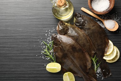 Photo of Fresh flounder fish, salt and products on black wooden table, flat lay with space for text. Raw seafood