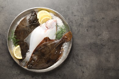 Photo of Fresh flounder fish, salt, lemon and dill on grey textured table, top view with space for text. Raw seafood