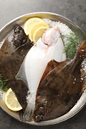 Photo of Fresh flounder fish, salt, lemon and dill on grey textured table, top view. Raw seafood