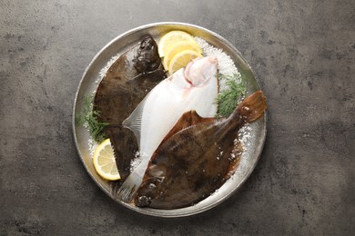 Photo of Fresh flounder fish, salt, lemon and dill on grey textured table, top view. Raw seafood