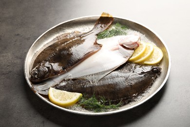 Photo of Fresh flounder fish, salt, lemon and dill on grey textured table, closeup. Raw seafood