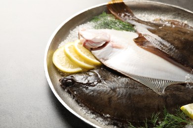 Photo of Fresh flounder fish, salt, lemon and dill on grey textured table, closeup. Raw seafood