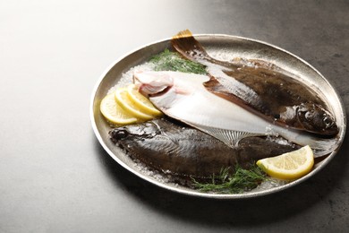 Photo of Fresh flounder fish, salt, lemon and dill on grey textured table, closeup. Raw seafood