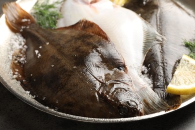 Photo of Fresh flounder fish, salt, lemon and dill on grey table, closeup. Raw seafood
