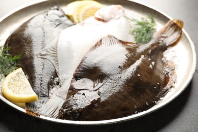 Photo of Fresh flounder fish, salt, lemon and dill on grey textured table, closeup. Raw seafood