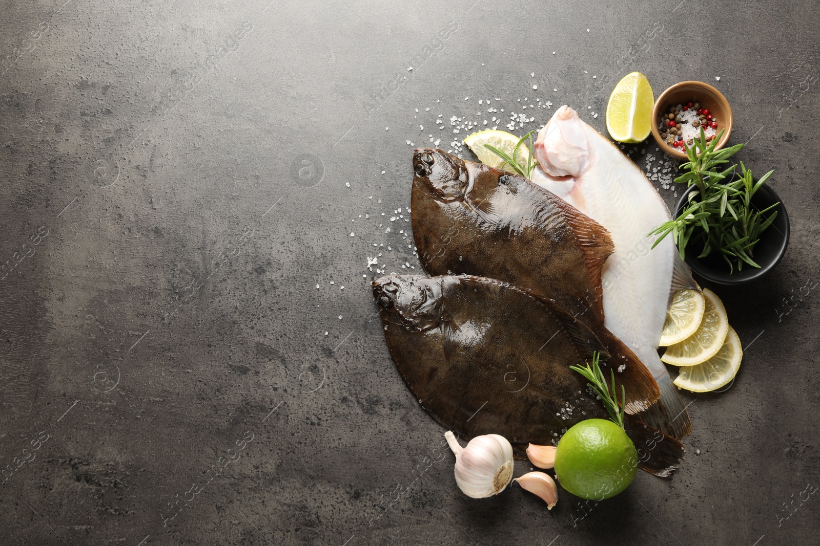 Fresh flounder fish, spices and products on grey textured table, flat lay with space for text. Raw seafood Photo of Fresh flounder fish, spices and products on grey textured table, flat lay with space for text. Raw seafood