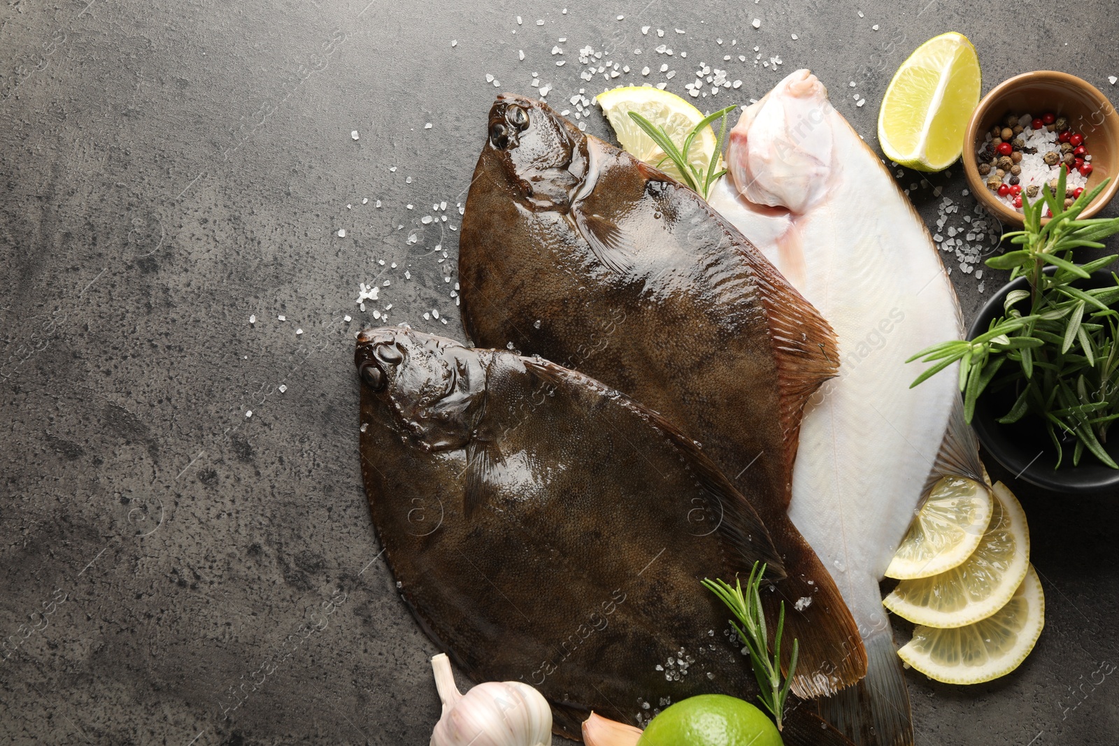 Fresh flounder fish, spices and products on grey textured table, flat lay with space for text. Raw seafood Photo of Fresh flounder fish, spices and products on grey textured table, flat lay with space for text. Raw seafood