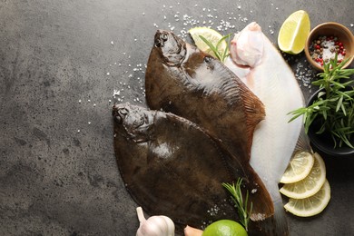 Photo of Fresh flounder fish, spices and products on grey textured table, flat lay with space for text. Raw seafood