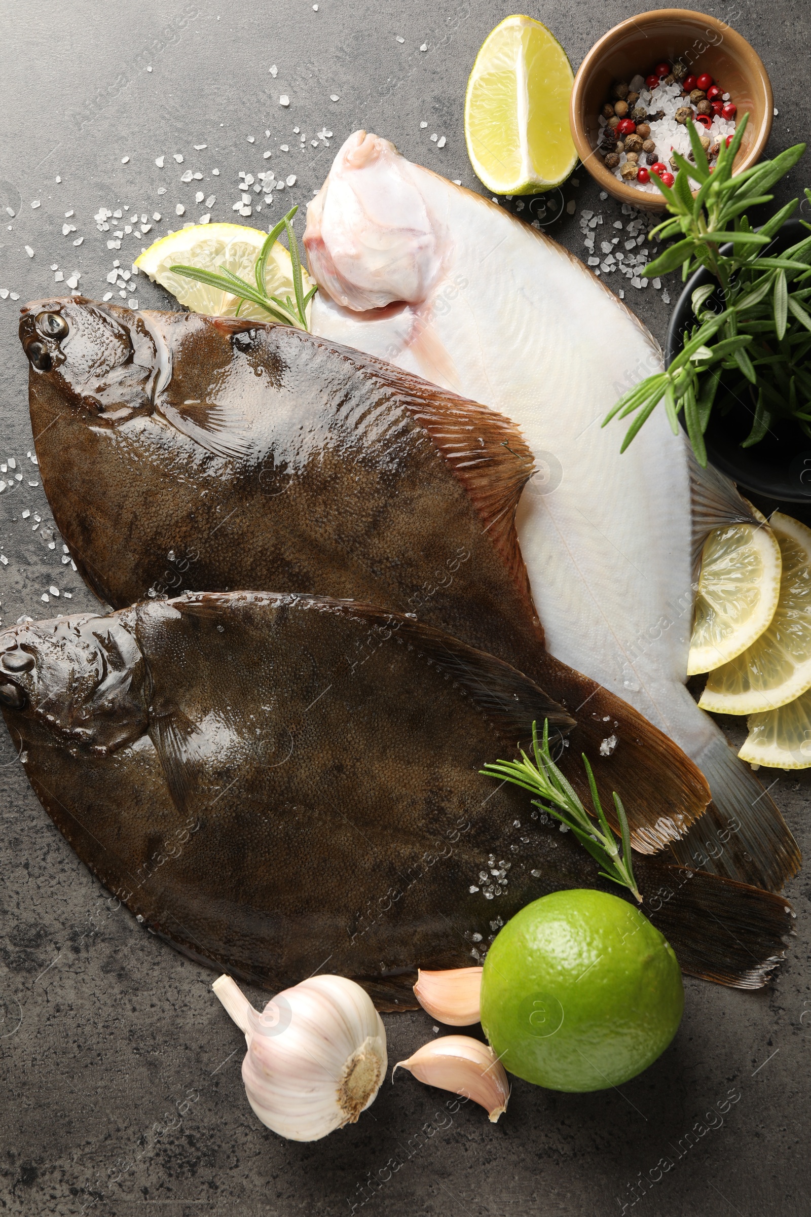 Photo of Fresh flounder fish, spices and products on grey textured table, flat lay. Raw seafood