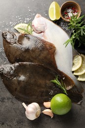 Photo of Fresh flounder fish, spices and products on grey textured table, flat lay. Raw seafood