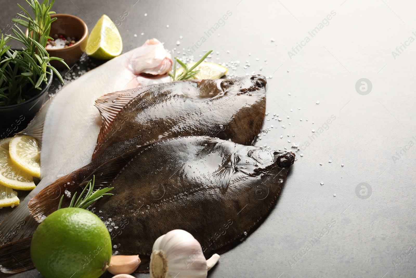 Photo of Fresh flounder fish, salt and products on grey textured table, closeup. Raw seafood