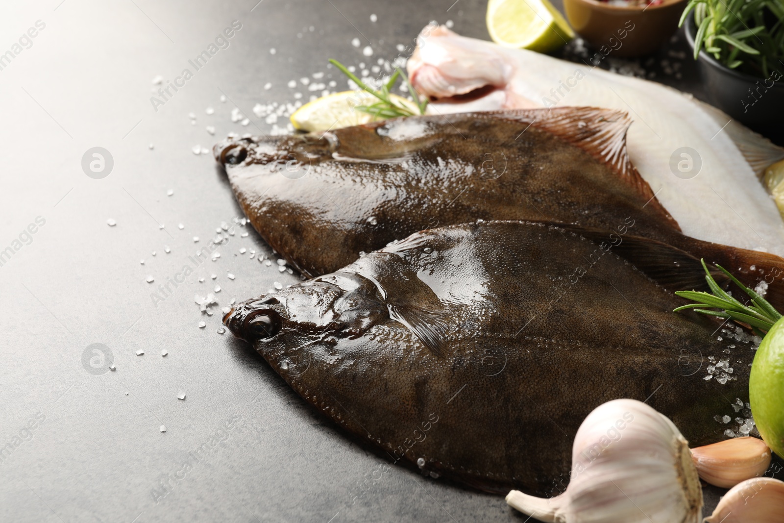 Photo of Fresh flounder fish, salt and products on grey textured table, closeup. Raw seafood