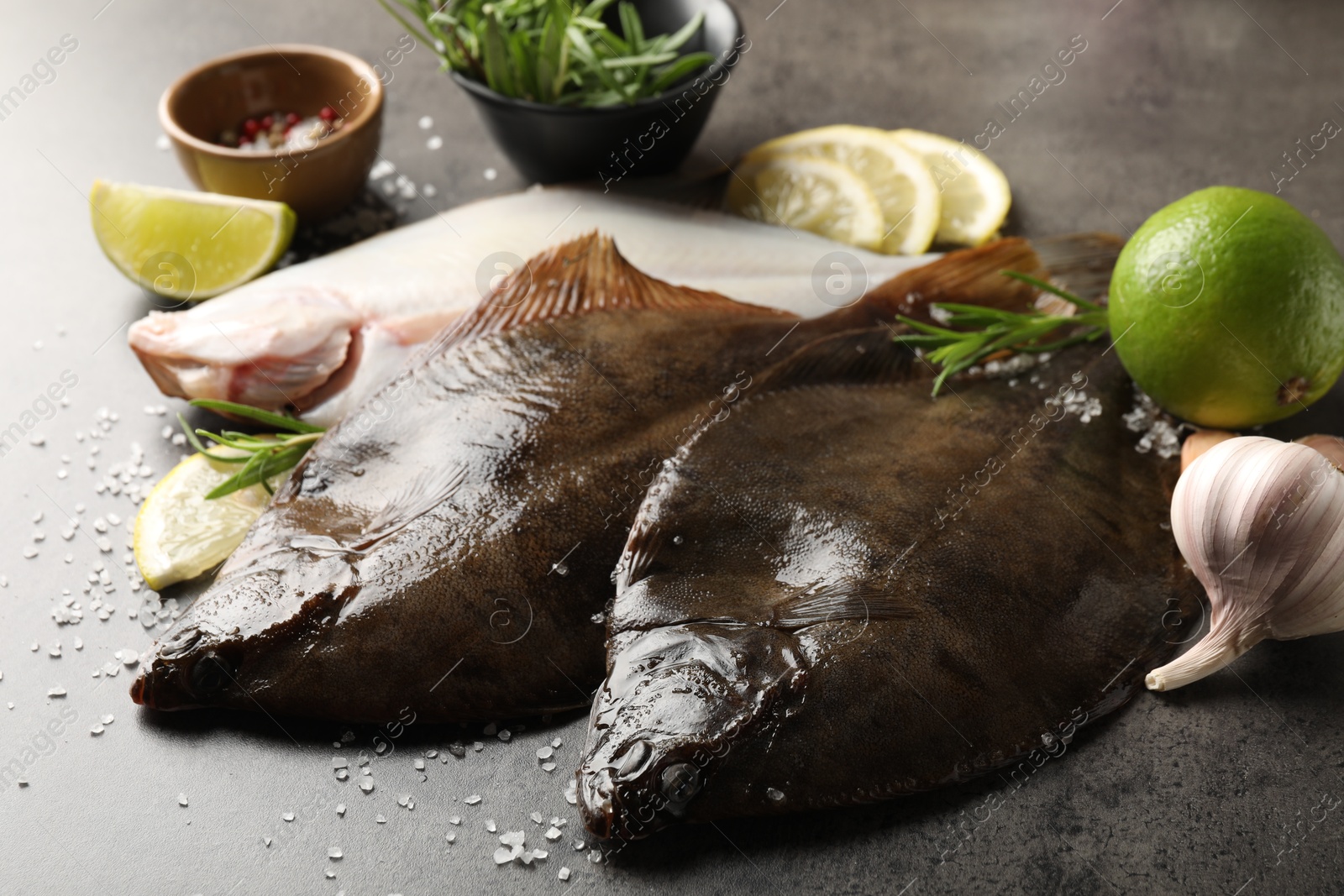 Photo of Fresh flounder fish, salt and products on grey textured table, closeup. Raw seafood
