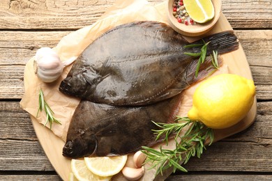 Photo of Fresh flounder fish, spices and products on wooden table, top view. Raw seafood