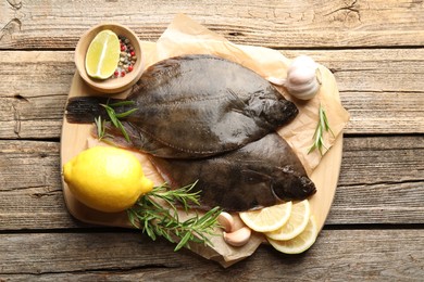 Photo of Fresh flounder fish, spices and products on wooden table, top view. Raw seafood