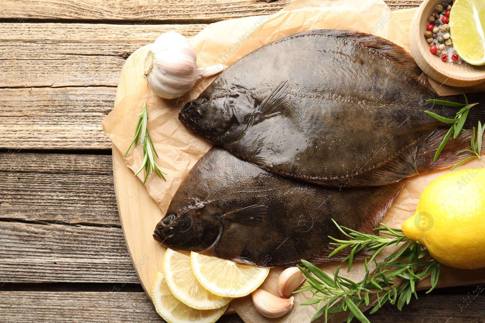 Photo of Fresh flounder fish, spices and products on wooden table, top view. Raw seafood