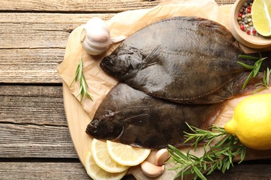 Photo of Fresh flounder fish, spices and products on wooden table, top view. Raw seafood