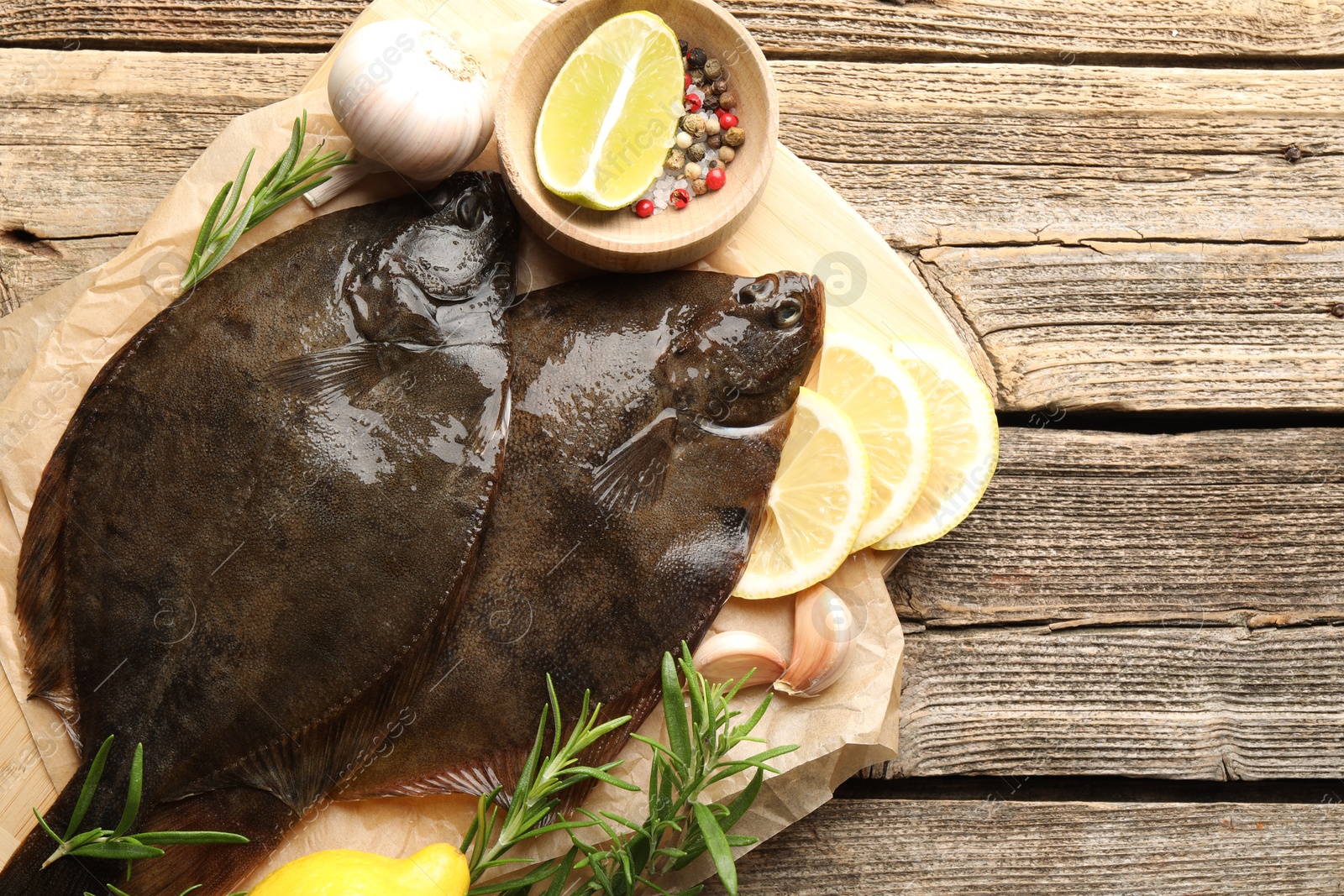 Photo of Fresh flounder fish, spices and products on wooden table, top view. Raw seafood