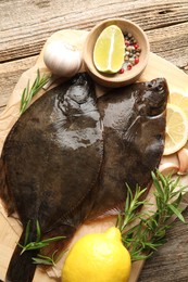 Photo of Fresh flounder fish, spices and products on wooden table, top view. Raw seafood