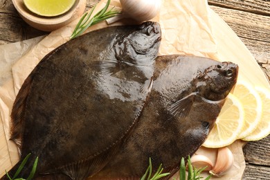 Photo of Fresh flounder fish, lemon and garlic on wooden table, flat lay. Raw seafood