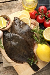 Photo of Fresh flounder fish, spices and products on wooden table, flat lay. Raw seafood
