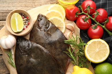 Photo of Fresh flounder fish, spices and products on wooden table, flat lay. Raw seafood