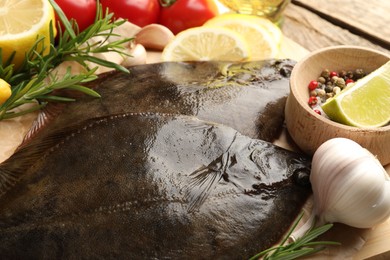 Photo of Fresh flounder fish, spices and products on wooden table, closeup. Raw seafood